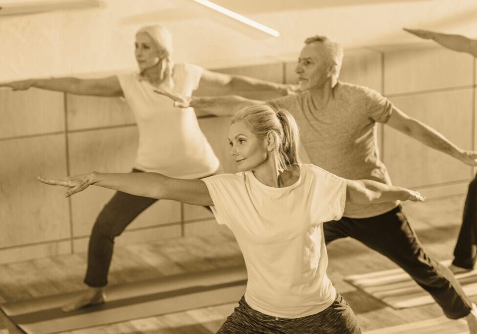 female instructor training with senior people in fitness studio